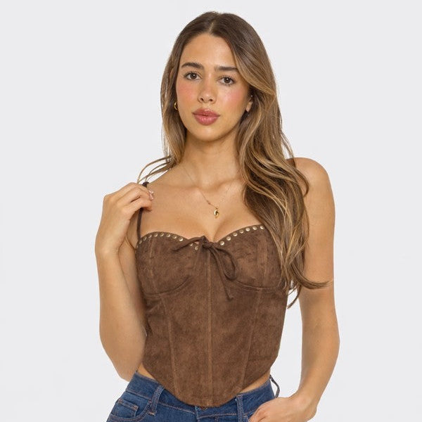 Woman wearing a brown suede top and blue jeans on a white background