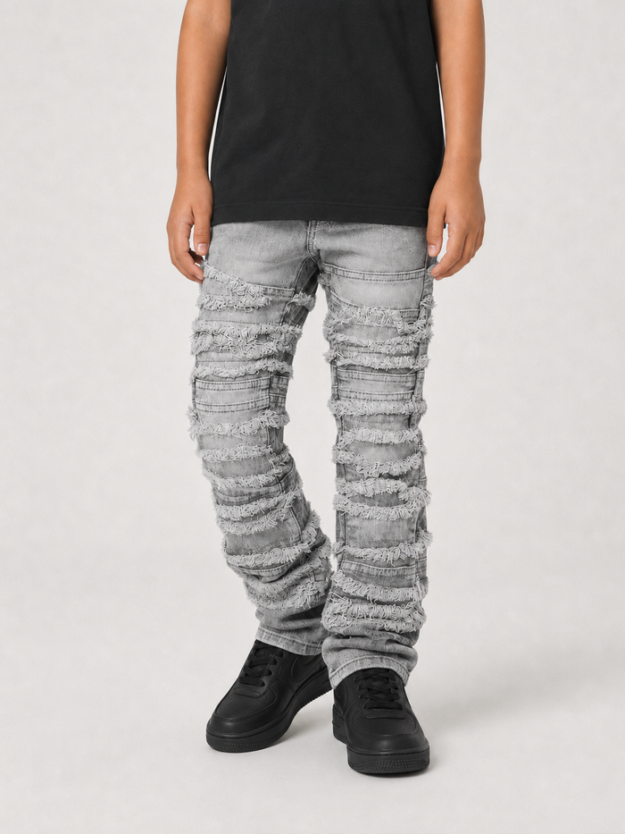 FWRD Kids distressed gray frayed stacked denim jeans showing a close-up of the distressed and frayed hem detail