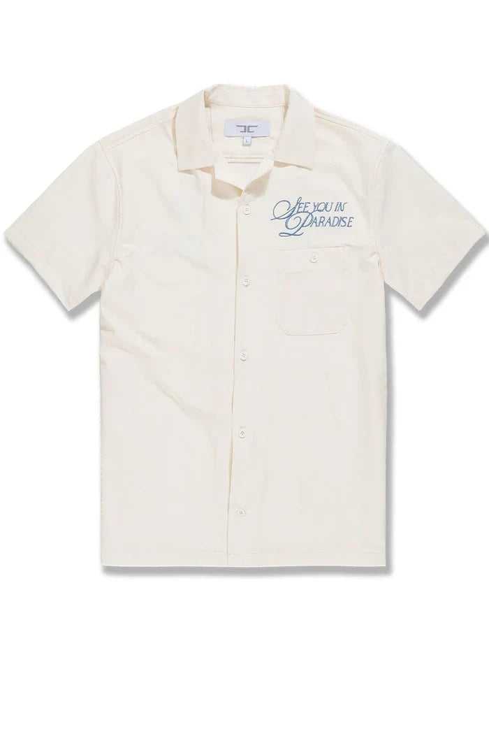 Cream SYIP See You in Paradise short sleeve button-up shirt with a relaxed fit and casual style, displayed on a hanger.