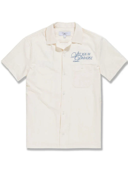 Cream SYIP See You in Paradise short sleeve button-up shirt with a relaxed fit and casual style, displayed on a hanger.
