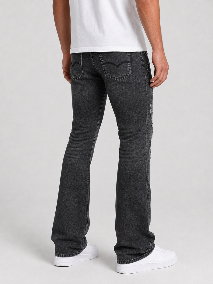 Taker frayed patched premium stretch stacked denim jeans in vintage black with distressed details and patchwork design.