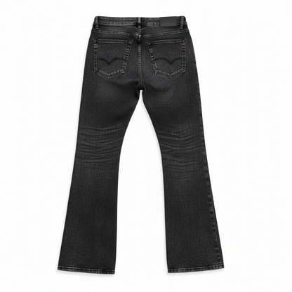 Close-up of Taker 'Frayed Patched' Premium Stretch Stack Denim in vintage black, showcasing distressed details and textured patchwork.
